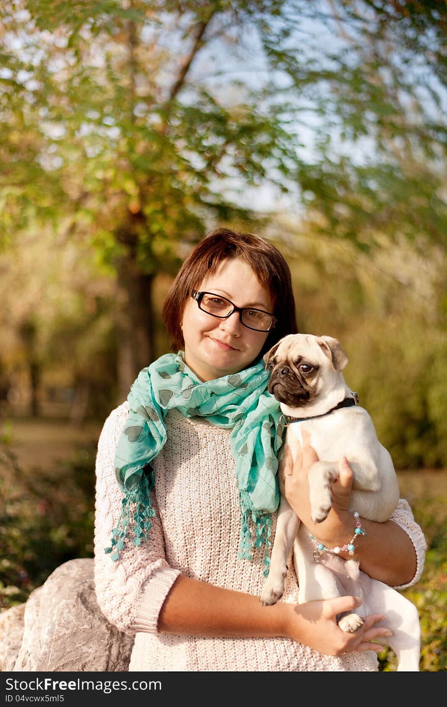 Outdoors woman in glasses holding a pug. Outdoors woman in glasses holding a pug