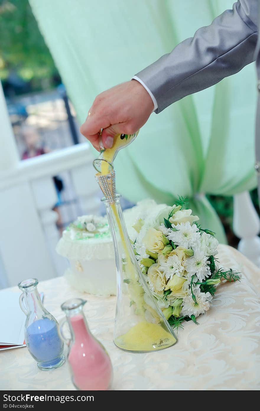 Man's hand pours colored sand in bottles