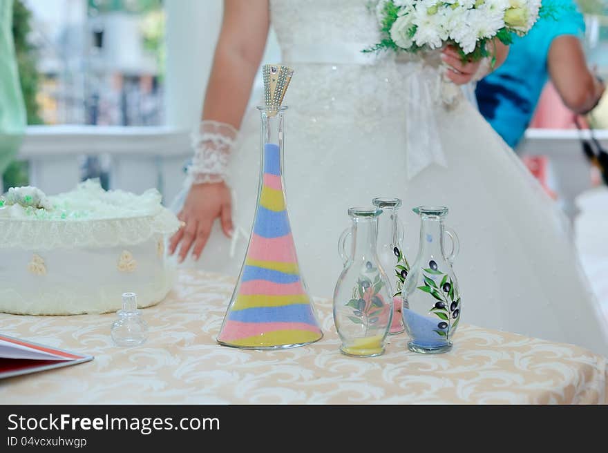 Beautiful bride's hands poured colored sand into a bottle. Beautiful bride's hands poured colored sand into a bottle