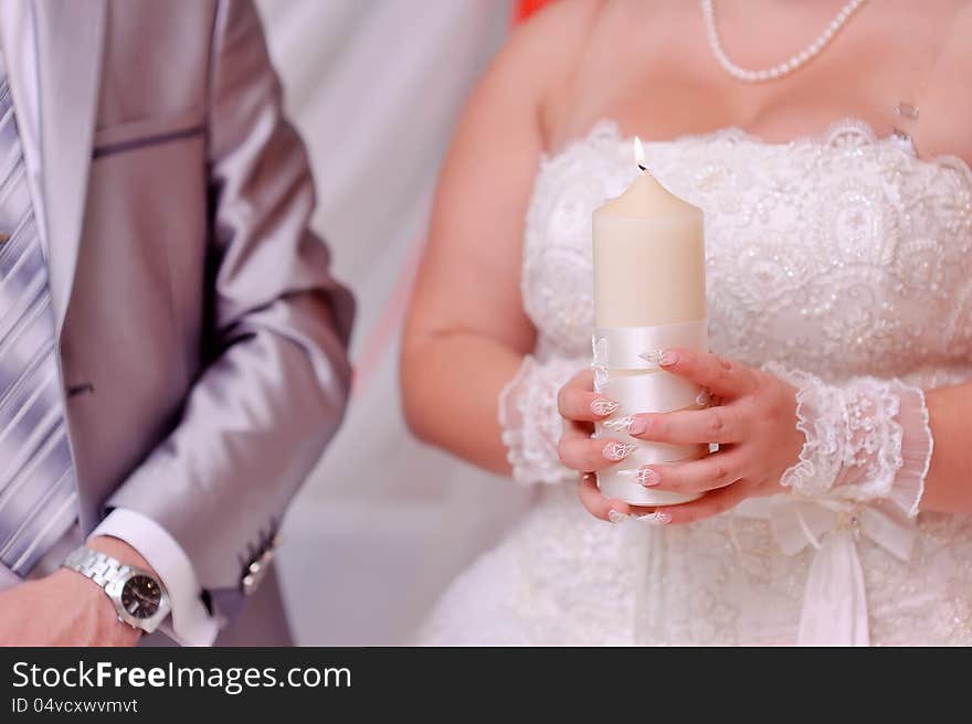 Beautiful bride's hands holding a large white candle. Beautiful bride's hands holding a large white candle