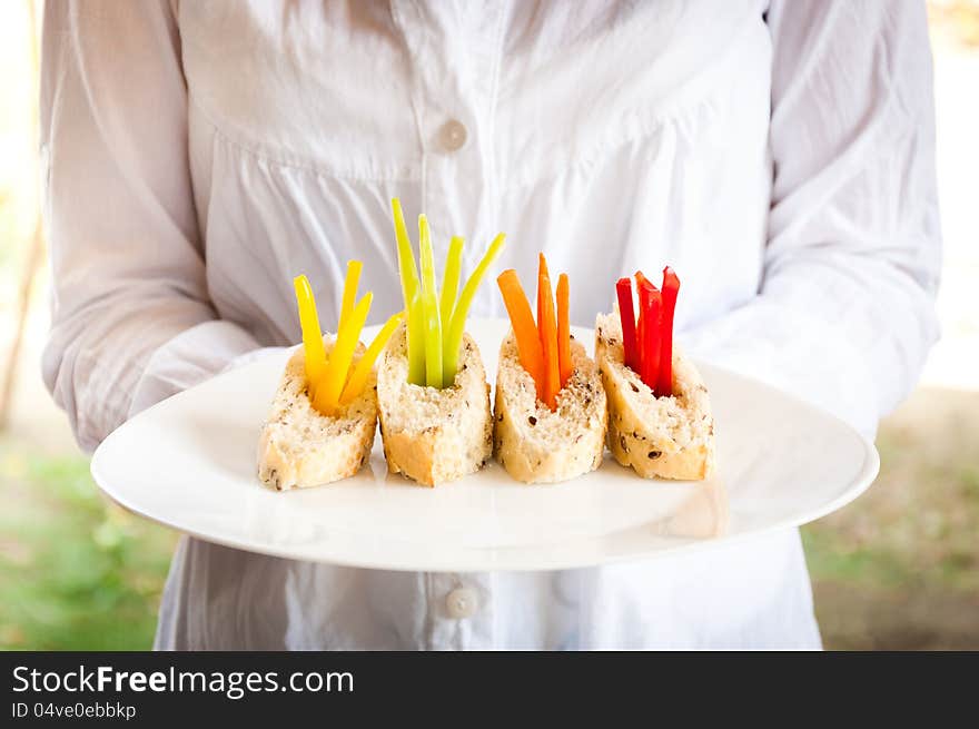 A waitress holding a plate of vegetarian catering food. A waitress holding a plate of vegetarian catering food