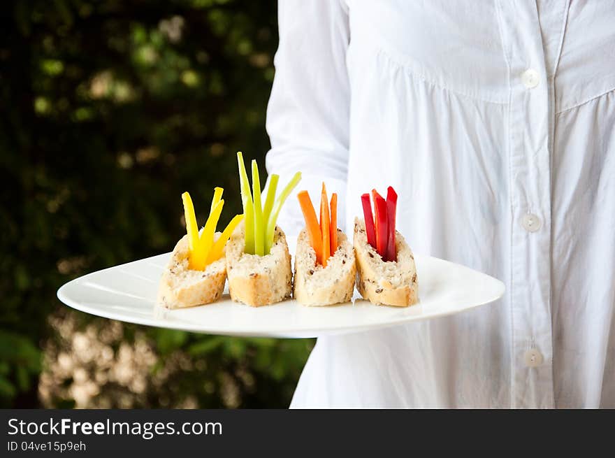 A waitress holding a plate of vegetarian catering food. A waitress holding a plate of vegetarian catering food