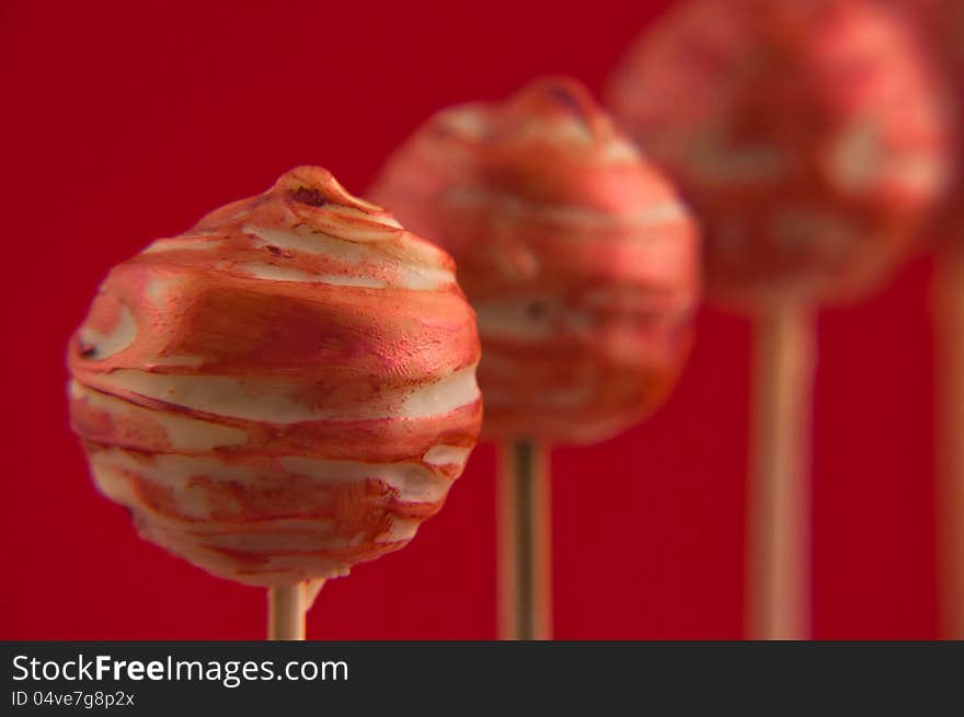 Red cake pops on wooden sticks on red background. Red cake pops on wooden sticks on red background