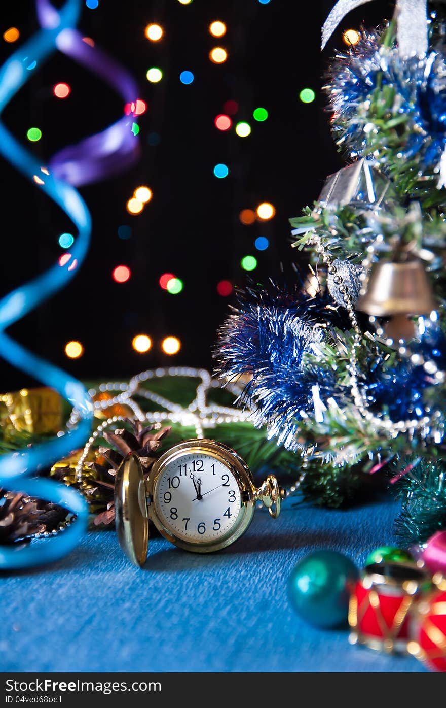 Round pocket watch,Christmas toys,a decorated Christmas tree,serpentine on a black background with lights. Round pocket watch,Christmas toys,a decorated Christmas tree,serpentine on a black background with lights