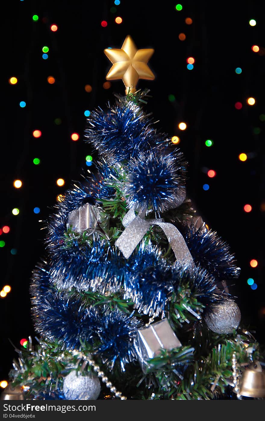 Dressed up fur-tree with the star on the top of his head on a black background with colored lights. Dressed up fur-tree with the star on the top of his head on a black background with colored lights