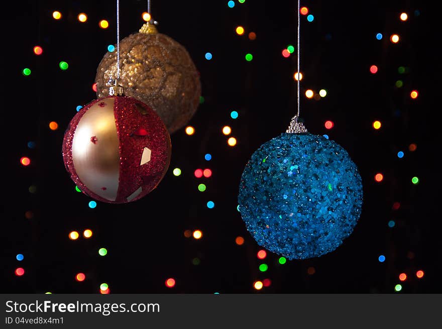 Three Christmas ball on a black background with lights