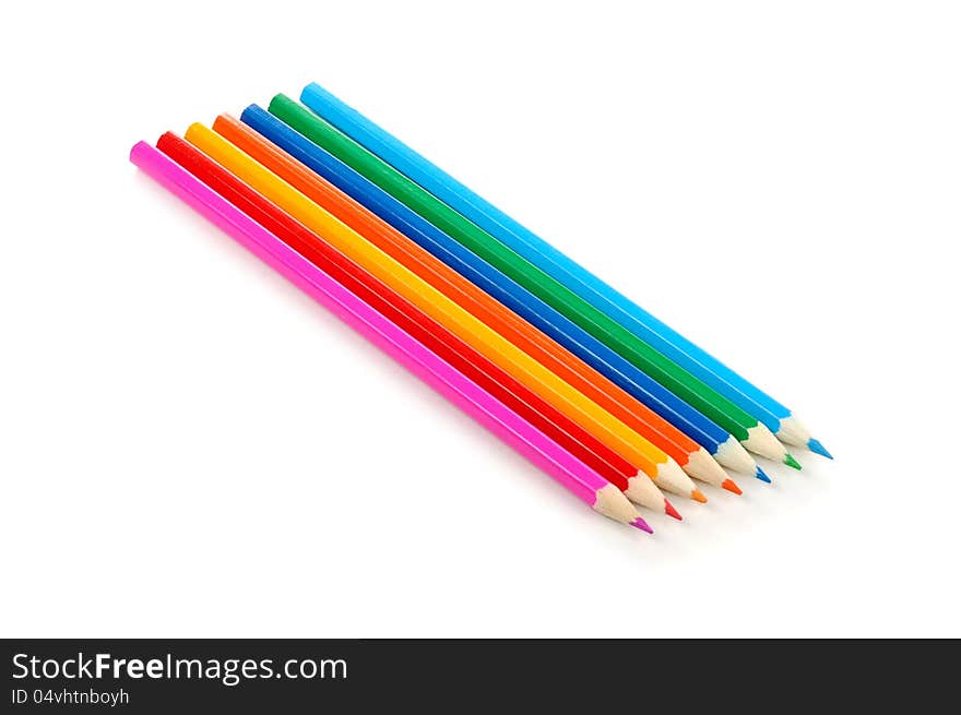 Seven multicolored pencils on a white background