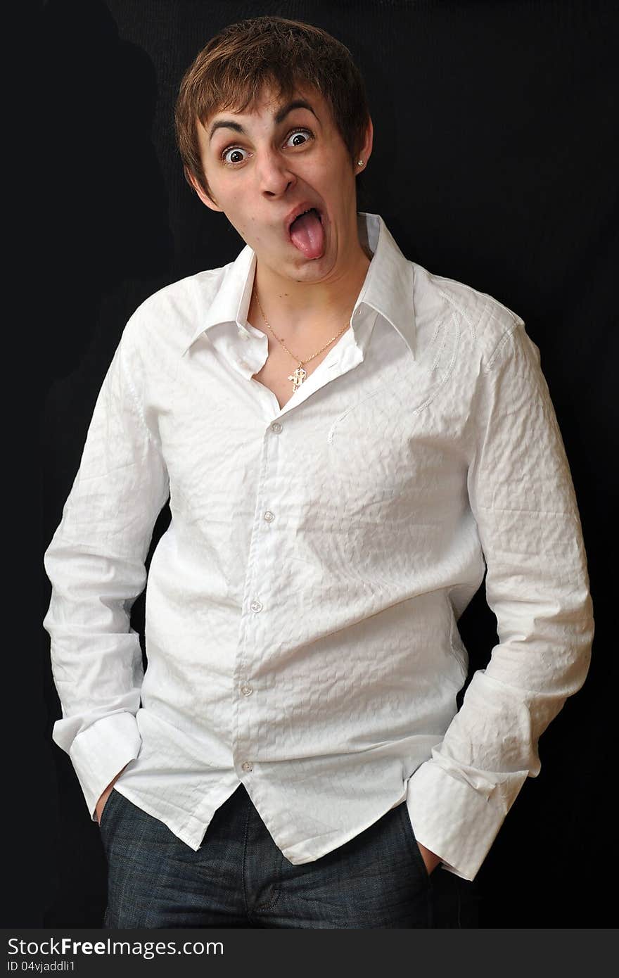 Emotional portrait of a guy in a white shirt with a stylish hairstyle on black background