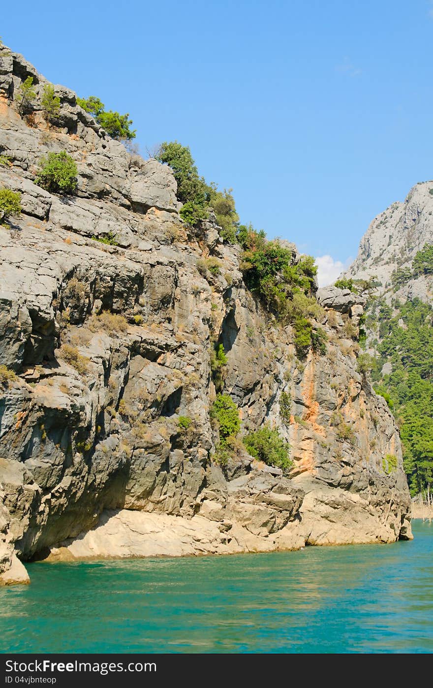 High mountains with growing trees and blue sky and lake. High mountains with growing trees and blue sky and lake