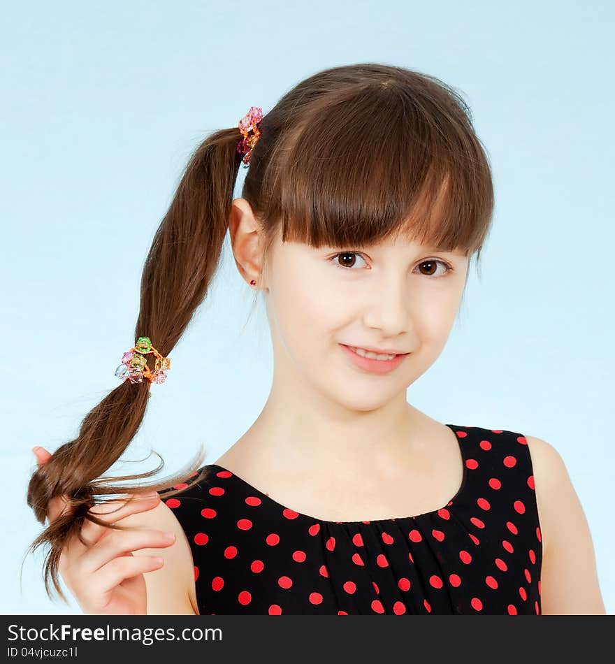 A young girl holds her hair in her hand smiling. A young girl holds her hair in her hand smiling