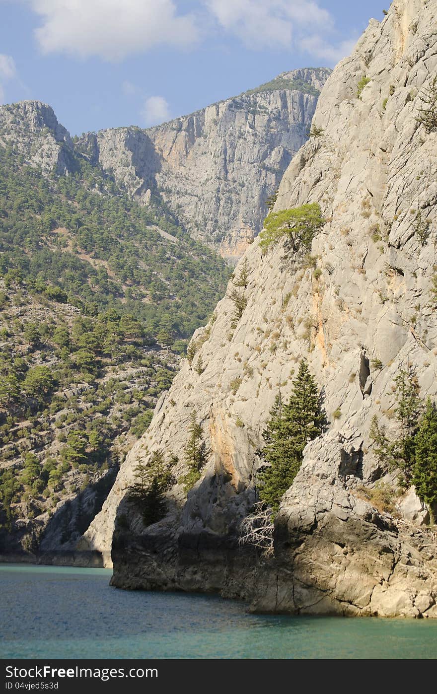 High mountains with growing trees and blue sky and lake. High mountains with growing trees and blue sky and lake