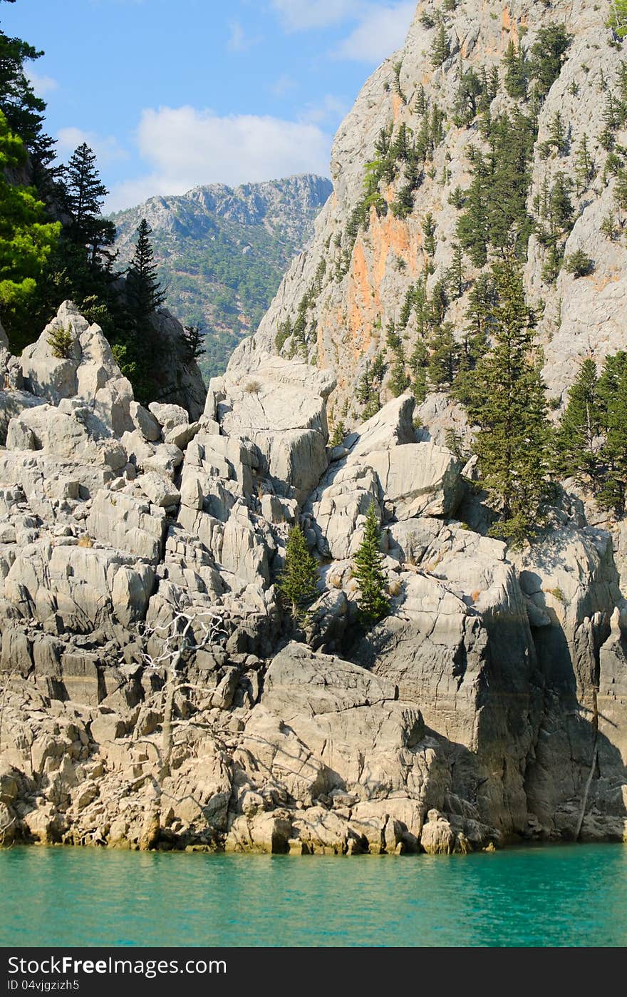 High mountains with growing trees and blue sky and lake. High mountains with growing trees and blue sky and lake