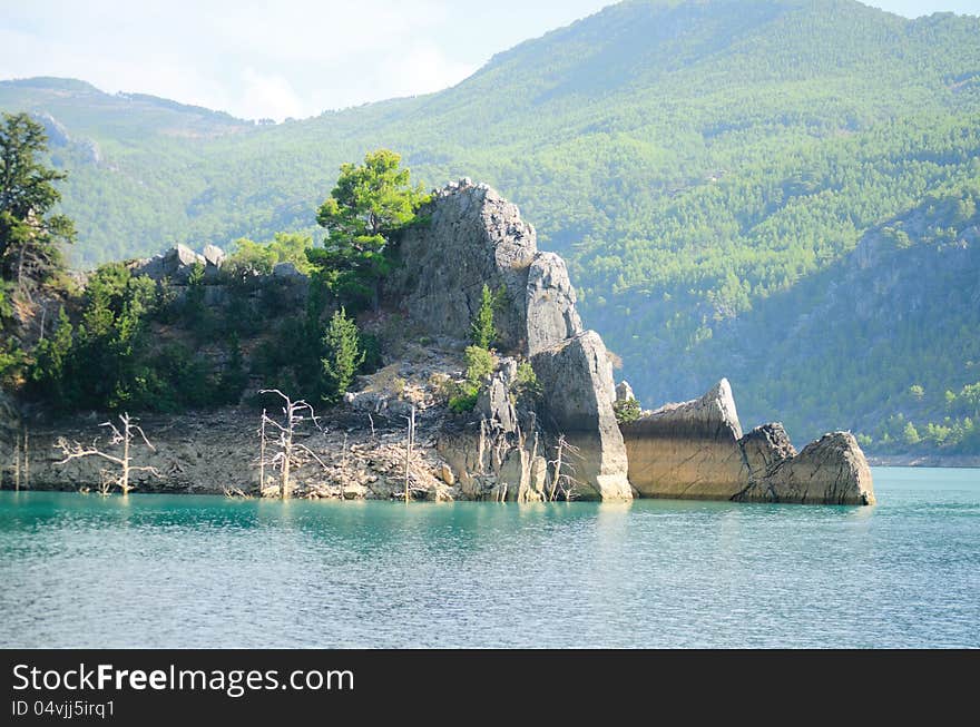 High mountains with growing trees and blue sky and lake. High mountains with growing trees and blue sky and lake