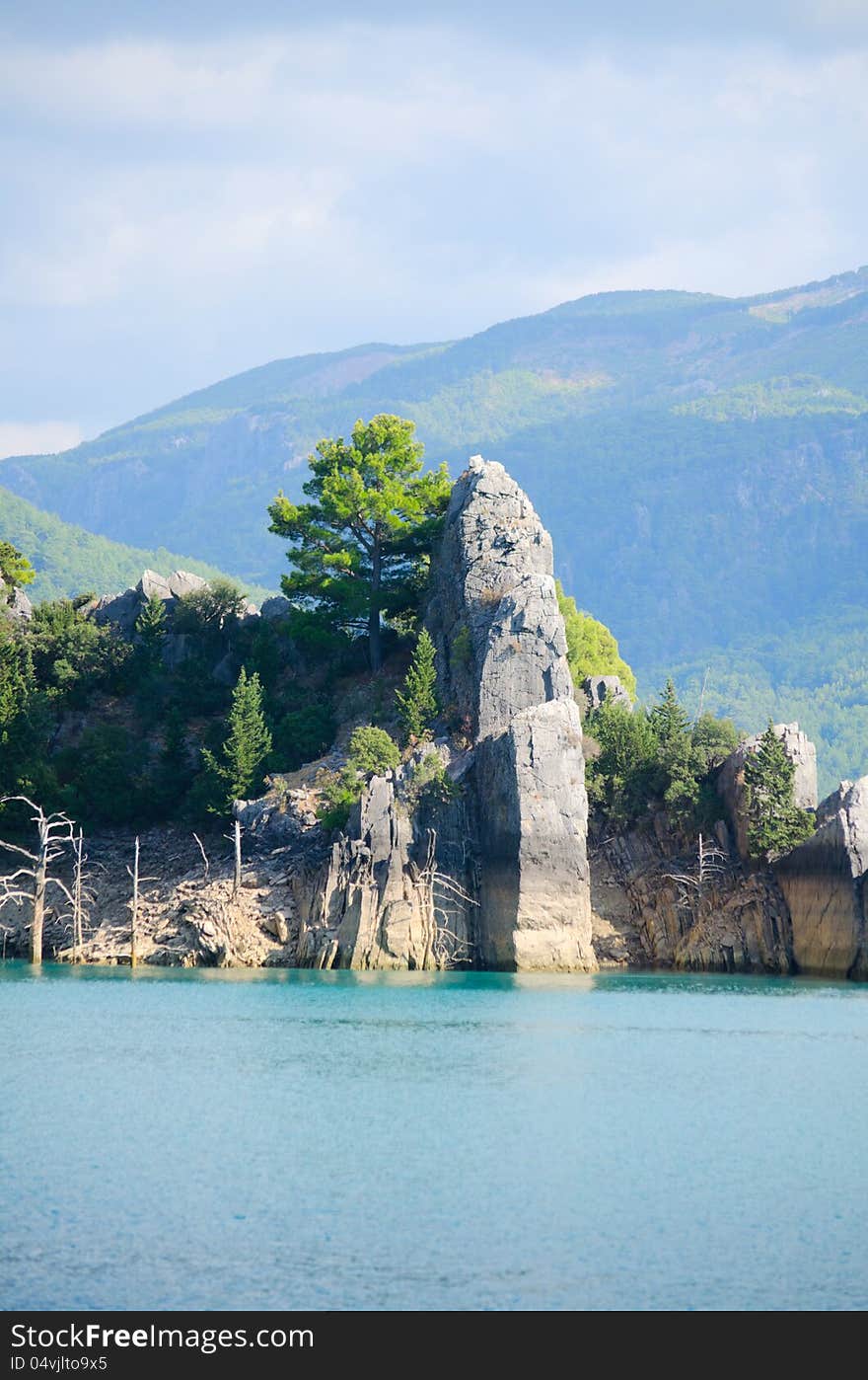 High mountains with growing trees and blue sky and lake. High mountains with growing trees and blue sky and lake