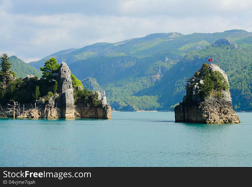 High mountains with growing trees and blue sky and lake. High mountains with growing trees and blue sky and lake