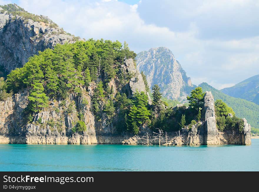 High mountains with growing trees and blue sky and lake. High mountains with growing trees and blue sky and lake