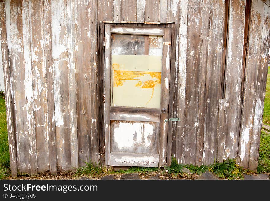 An old building with a peeling paint wood texture and a very old door on a shed or barn creates an abstract background image. An old building with a peeling paint wood texture and a very old door on a shed or barn creates an abstract background image.