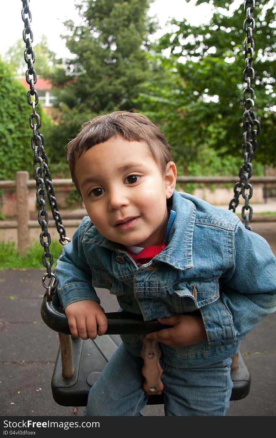 Little cute boy playing on a swing.