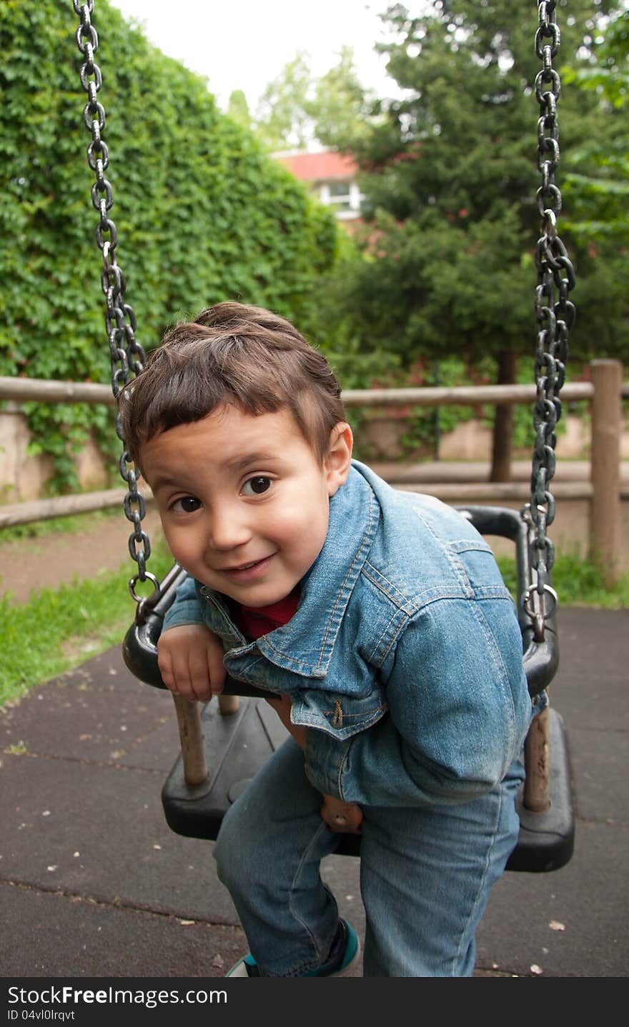 Little cute boy playing on a swing