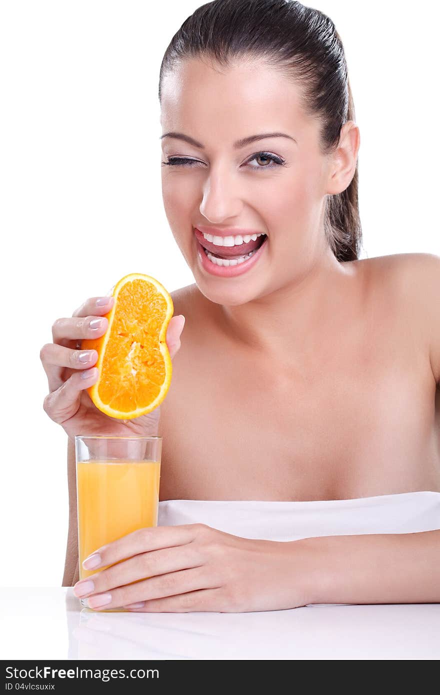 Portrait of young pretty smiling woman holding orange and squeezes the juice from the orange into a glass. Natural fresh juice concept. Portrait of young pretty smiling woman holding orange and squeezes the juice from the orange into a glass. Natural fresh juice concept