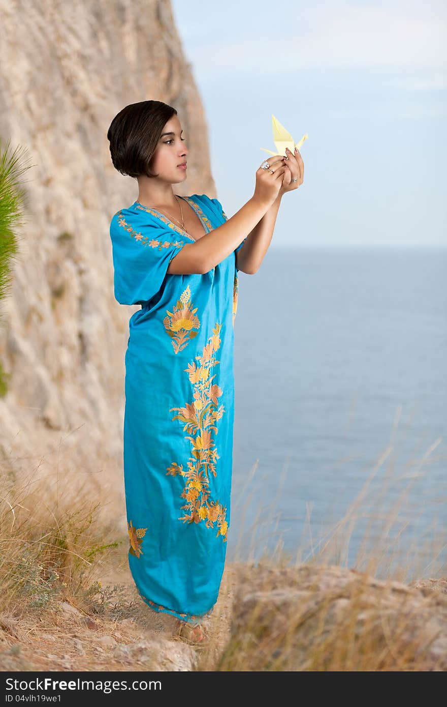 Girl in blue indian dress with origami on seacoast. Girl in blue indian dress with origami on seacoast