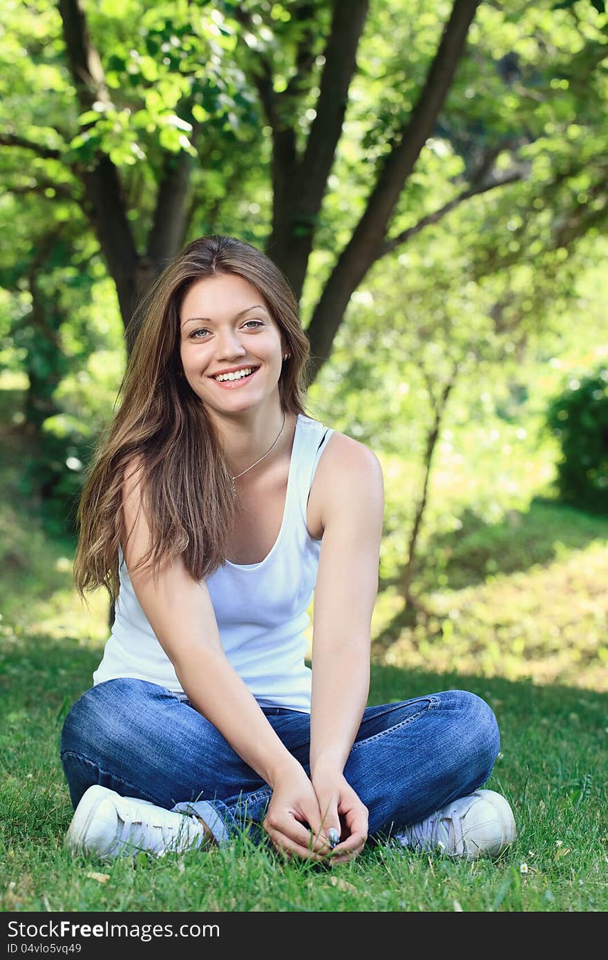 Young girl siting on grass in park and smiling. Young girl siting on grass in park and smiling