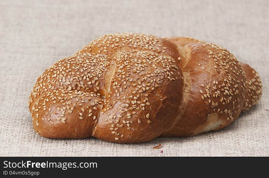 Roll of white loaf strewed with sunflower seeds on a gray background. Roll of white loaf strewed with sunflower seeds on a gray background