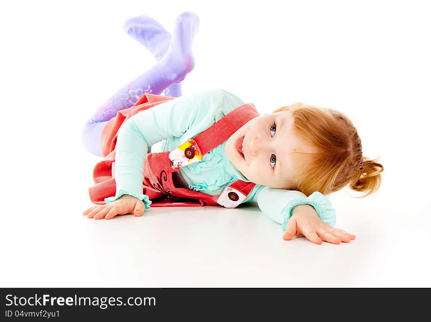 A little girl in a red dress, lying posing isolated on white background