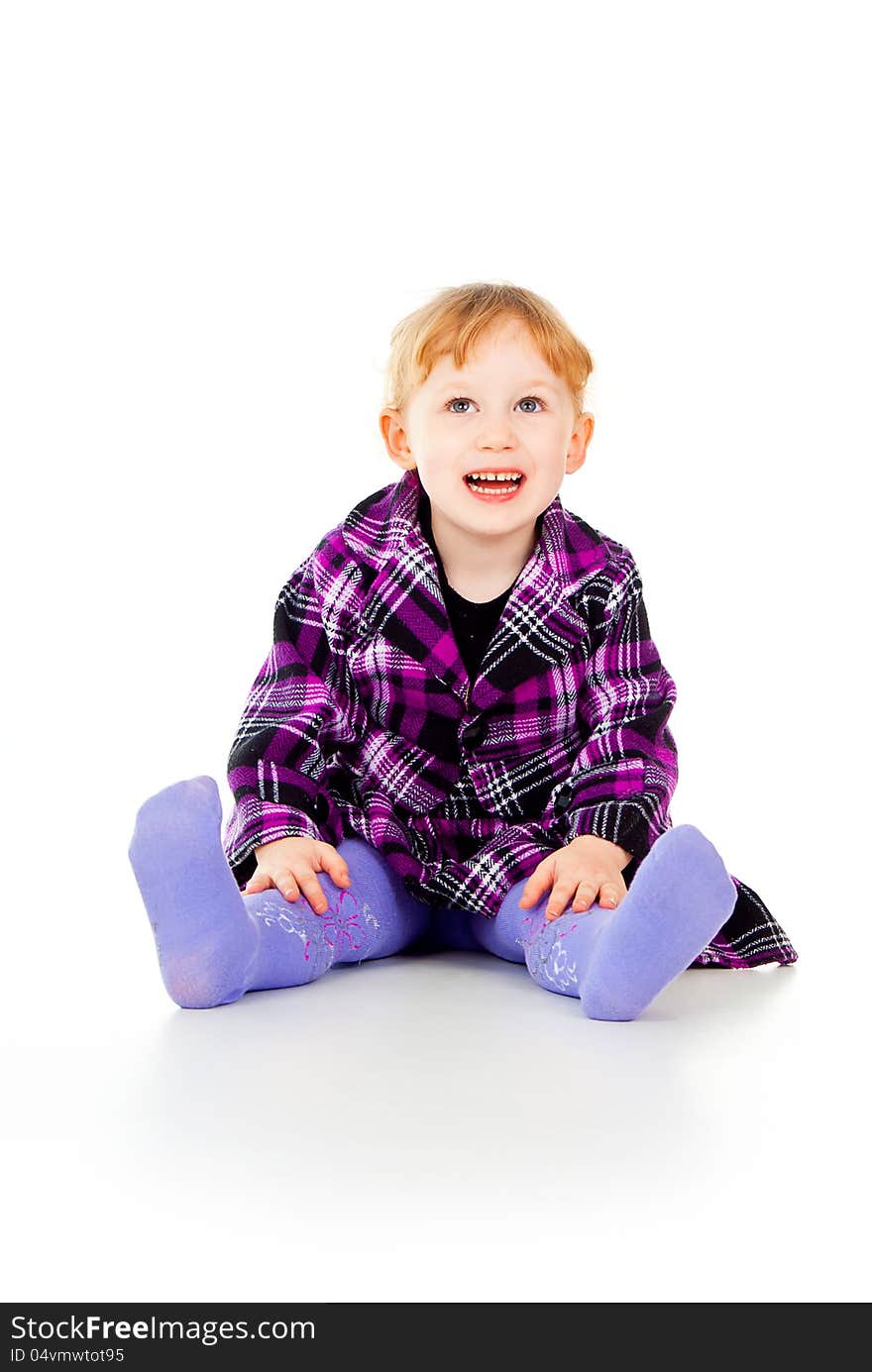 A little girl in a dress, have fun, sits isolated on white background