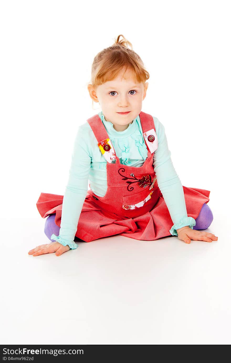 A little girl in a red dress, sitting poses isolated on white background