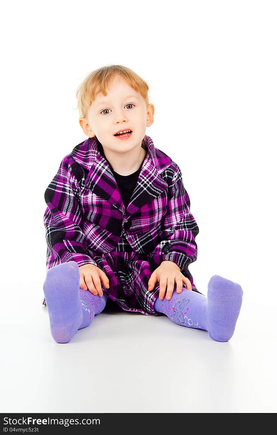 A little girl in a dress, have fun, sits isolated on white background