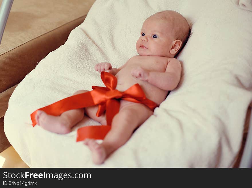 Naked baby lying on a blanket with a red ribbon. Naked baby lying on a blanket with a red ribbon