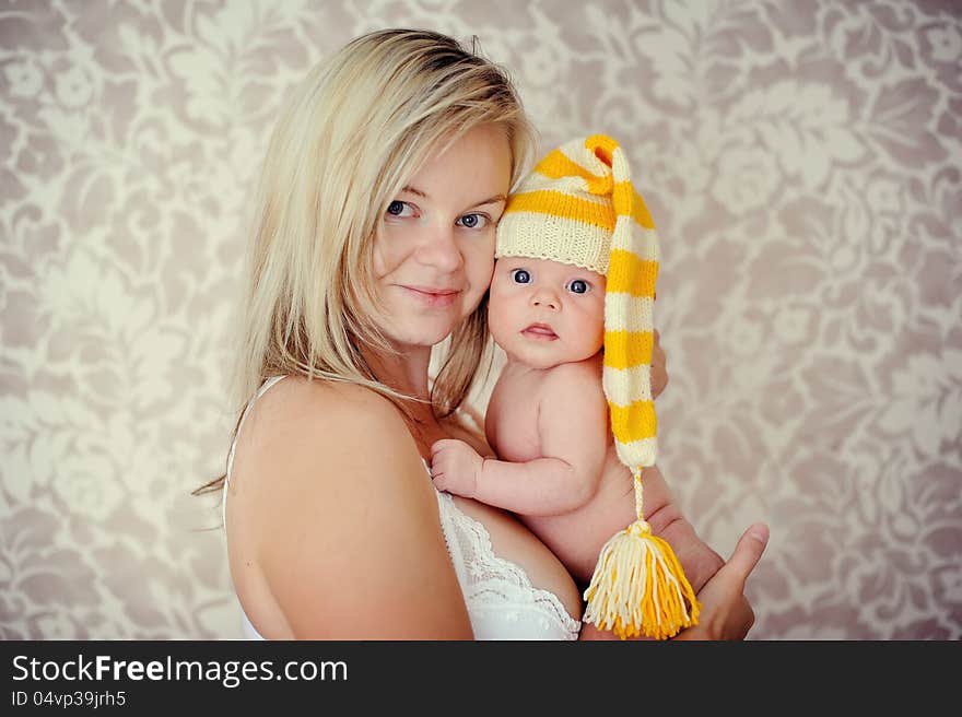 Delicate and feminine mother tenderly hugging her baby in the cap. Delicate and feminine mother tenderly hugging her baby in the cap