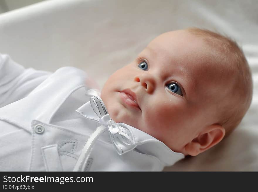 On a white background cute baby lying in a beautiful dress. On a white background cute baby lying in a beautiful dress