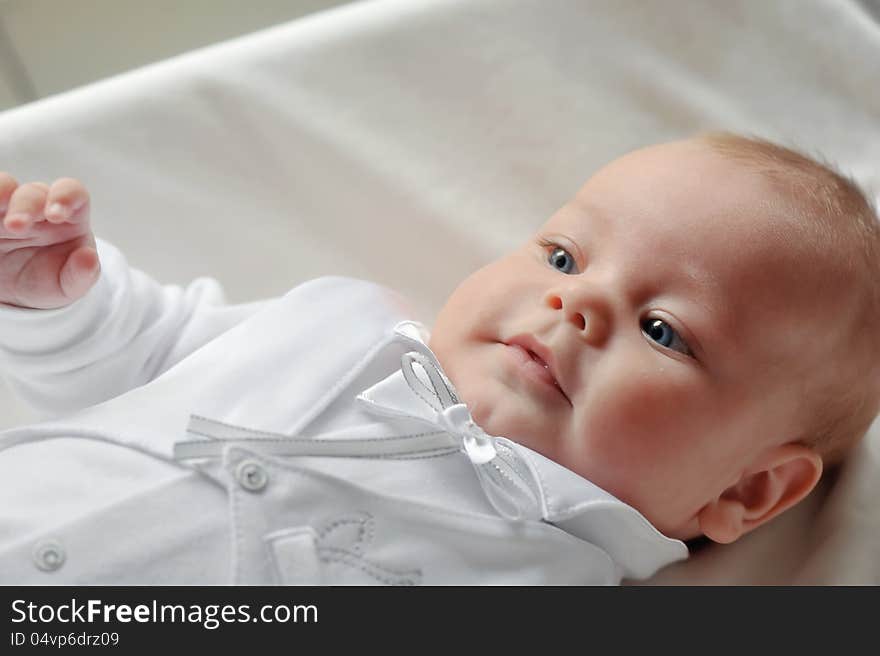 On a white background cute baby lying in a beautiful dress. On a white background cute baby lying in a beautiful dress