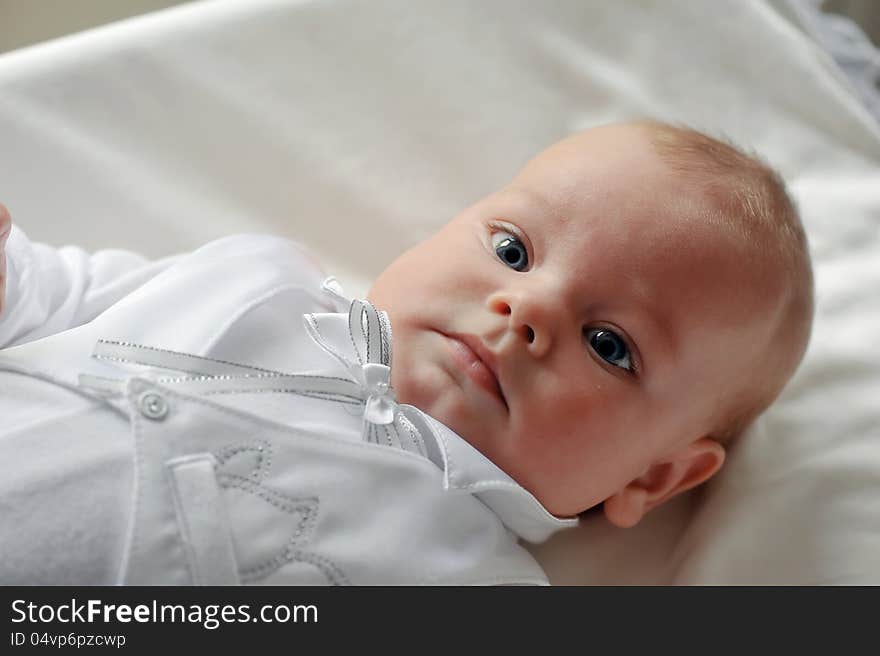 On a white background cute baby lying in a beautiful dress. On a white background cute baby lying in a beautiful dress