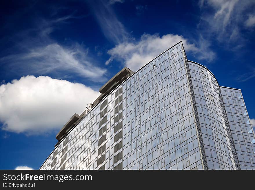 A modern glass skyscraper on a blue sky background. A modern glass skyscraper on a blue sky background