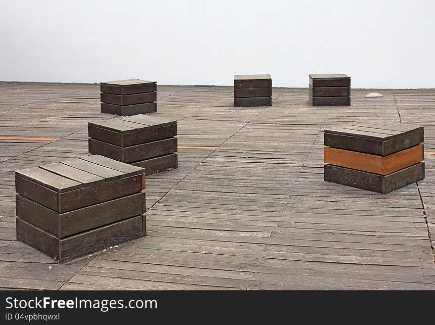 Square wooden chairs on the wooden floor in front of a white wall