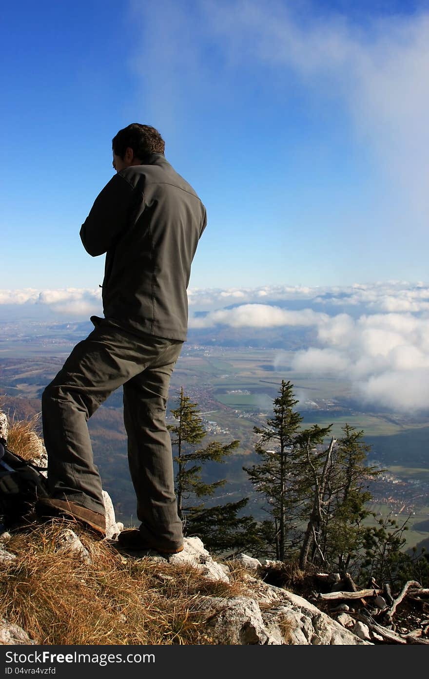 This image presents a young man admiring the view from the top of the mountain in Piatra Craiului, Romania .
