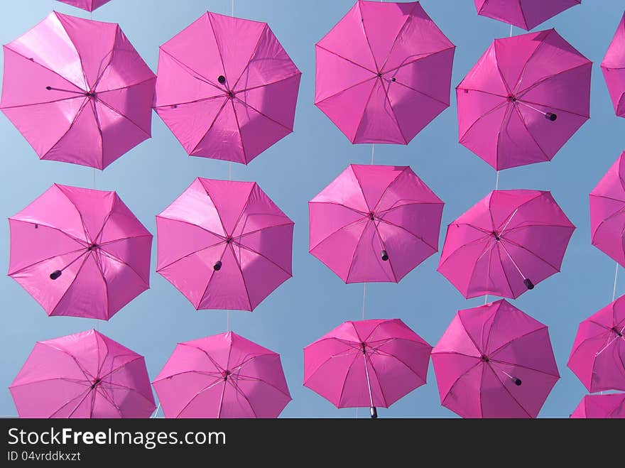 Pink umbrellas stacked above the street advertising purposes