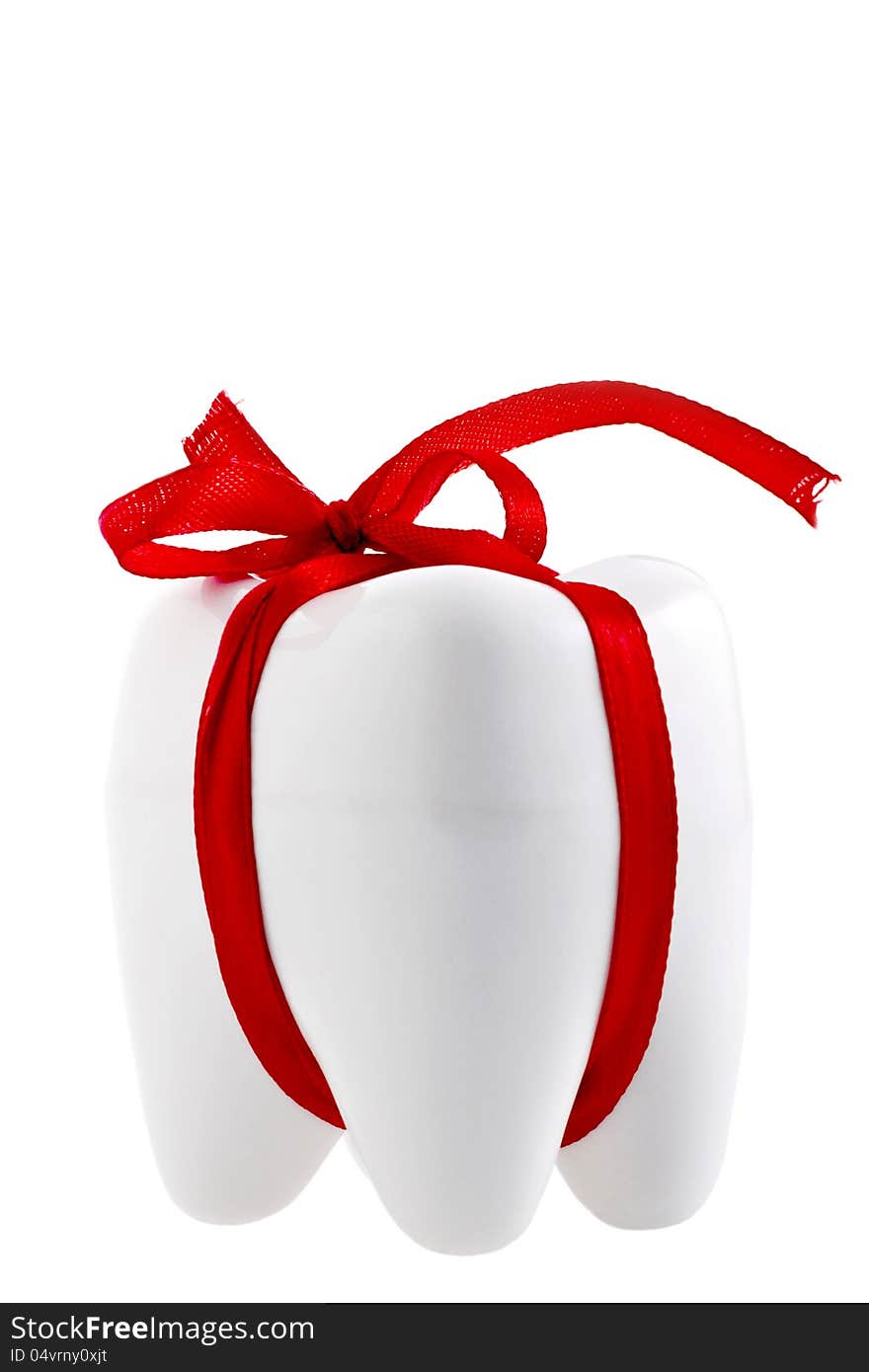 Artificial festive human tooth shape with a festive red ribbon isolated on white