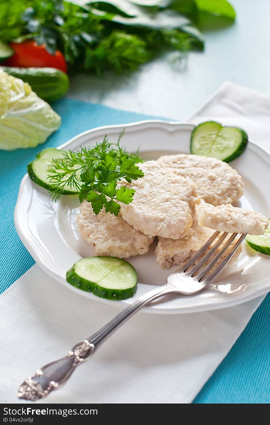 Dietary Cutlets on Pair on a White Plate with Pieces of Cucumber. Dietary Cutlets on Pair on a White Plate with Pieces of Cucumber