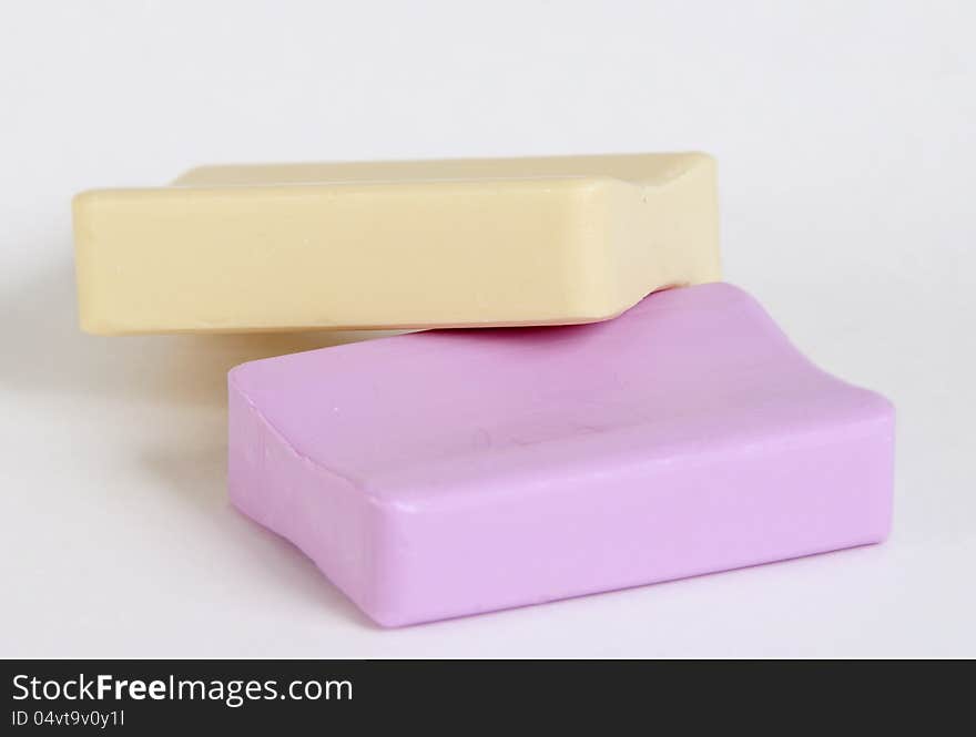 Two new pieces of soap, pink and yellow, on a white background