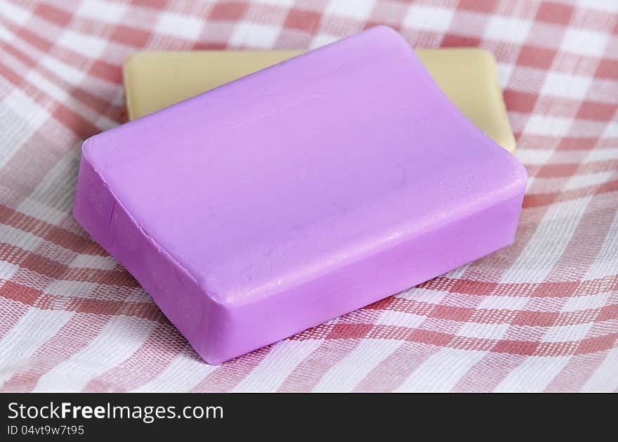 Two new pieces of soap, pink and yellow, on a checkered napkin