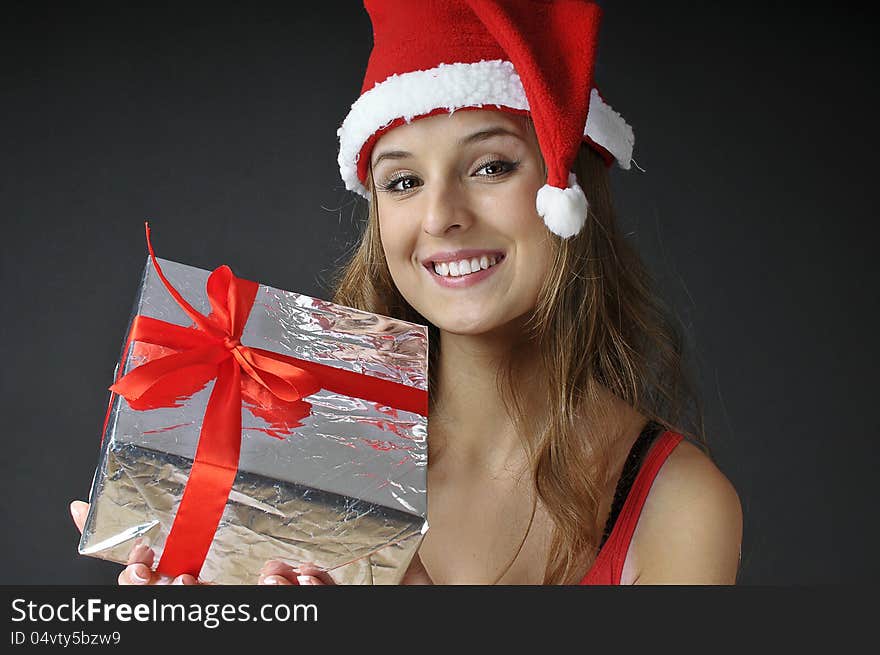 Christmas smiling girl holds gift wearing Santa hat. Christmas smiling girl holds gift wearing Santa hat.