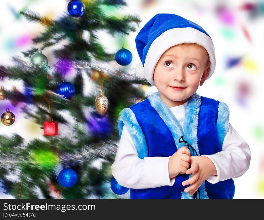 Boy in a cap of Santa Claus on Christmas tree background