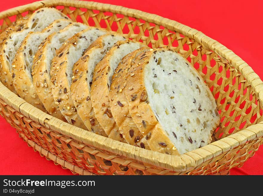 Fresh white bread pieces with whole seeds in a wicker basket on a red napkin. Fresh white bread pieces with whole seeds in a wicker basket on a red napkin