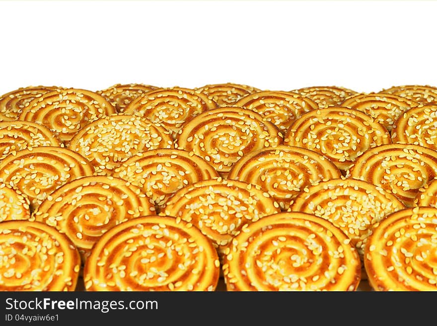 Round cookies with sesame seeds laid out in rows on a white background