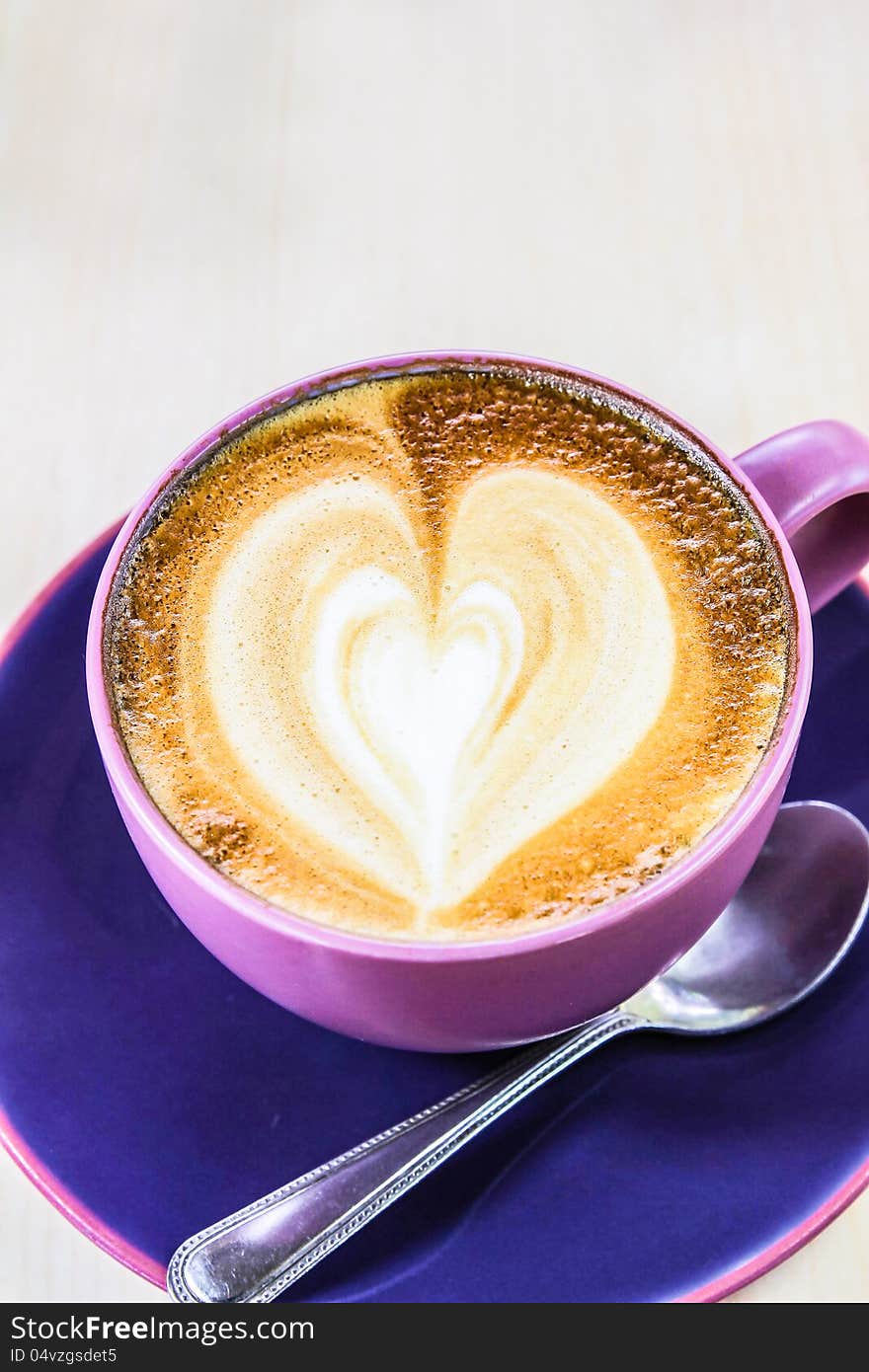 Cappuccino coffee with heart drawing in blue cup