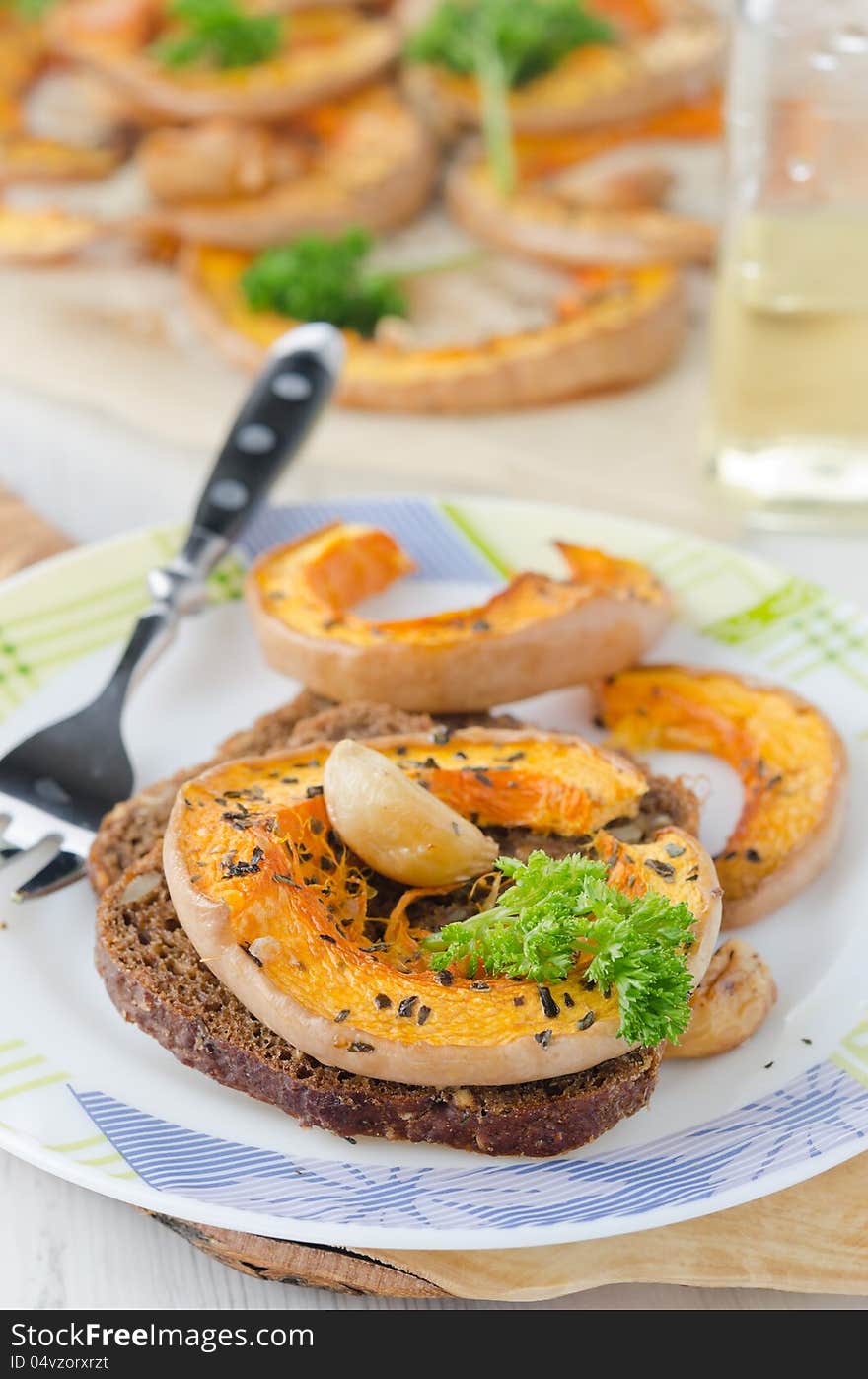 Appetizer - sliced ​​pumpkin baked with garlic and corn bread on a plate. Appetizer - sliced ​​pumpkin baked with garlic and corn bread on a plate